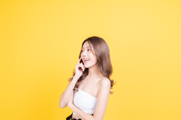 skin care concept. porprait posing asia beauty woman hand touch face and shoulder with yellow background studio shooting