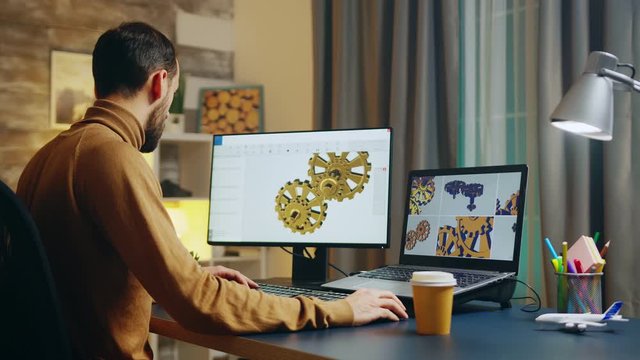 Bearded engineer taking a sip of coffee while working on computer