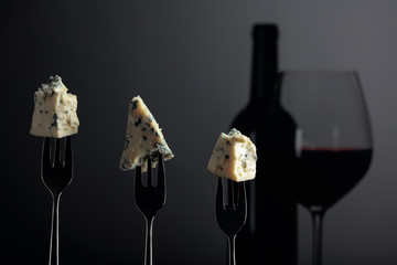 Pieces of blue cheese on a forks and red wine.