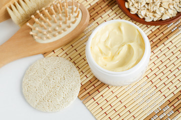 Yellow facial mask (banana face cream, shea butter hair mask or body butter) in the small white jar. Natural skin and hair concept.
