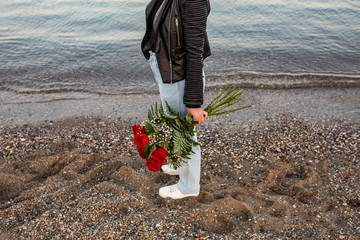 Fototapeta premium WOMAN WALKING WHIT BOUQUET OF ROSES ON THE BEACH