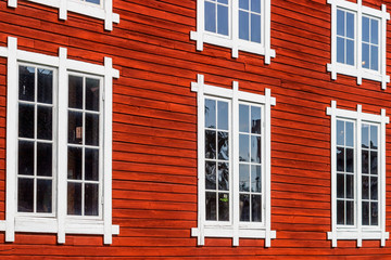 Fototapeta na wymiar Red wooden facade with beautiful windows