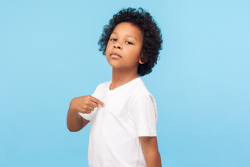 This is me. Portrait of preschool curly boy in T-shirt being proud and arrogant pointing at himself...