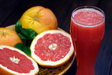 Naklejka na ściany i meble A glass of fresh grapefruit juice and grapefruit fruits on a wooden table. Healthy food. 