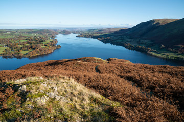 Beautiful Autumn Fall landscape of Ullswater and surrounding mountains and hills viewed from Hallin Fell on a crisp cold morning with majestic sunlgiht on the hillsides