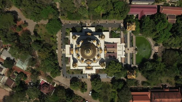 Top down tracking Aerial view of Buu Long Pagoda, a beautiful Buddhist temple with large gold roof structure in Saigon, Ho Chi Minh City, Vietnam on a sunny clear day