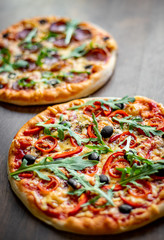 Pepperoni Pizza and Pizza with Mozzarella cheese, Tomatoes, pepper, olive, Spices and Fresh arugula. Pizza Margherita or Margarita on wooden table background