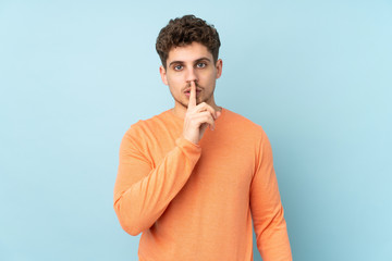 Caucasian man isolated on blue background showing a sign of silence gesture putting finger in mouth