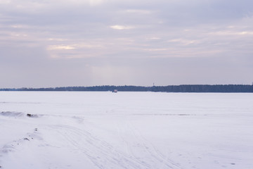 Obraz premium Landscape of a frozen lake in winter. The surface of the water in the lake is covered with snow and ice.