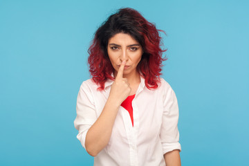 Falsehood sign. Portrait of angry displeased woman with fancy red hair in white shirt touching nose with lie gesture, blaming for deceit, forgery. indoor studio shot isolated on blue background