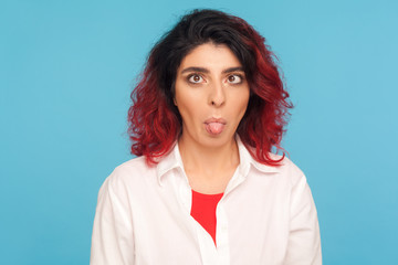 Portrait of silly dumb hipster woman with fancy red hair doing crossing eyes and sticking out...