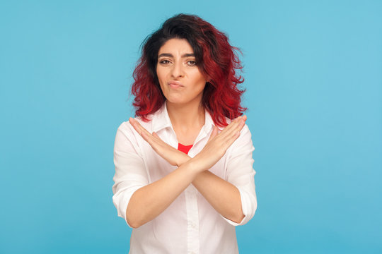 Never, no compromise! Portrait of dissatisfied hipster woman with fancy red hair crossing hands, showing x sign, ban or prohibition gesture, rejecting offer. studio shot isolated on blue background