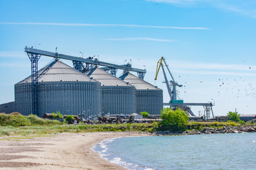 Large grain elevator silos in port with flying birds and sea coast (Port of Liepaja, Latvia) © Abinieks