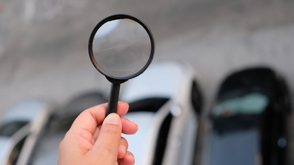 magnifying glass in hand car on background