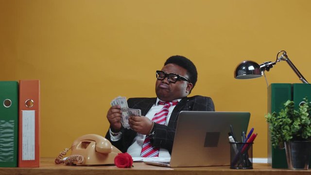 Satisfied african employee receives bunch of money on payday. Handsome happy black businessman counts money banknotes working at modern office corporation.