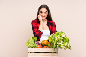 Farmer with freshly picked vegetables in a box isolated on beige background nervous and scared