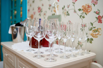 Sparkling glassware on dinner table and bottle of wine in bucket in restaurant, copy space. Crystal glasses ready for celebration. Wineglasses at luxury wedding reception