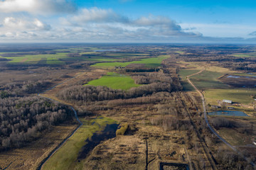 Aerial landscape view of a green and brown rural area under cloudy blue sky