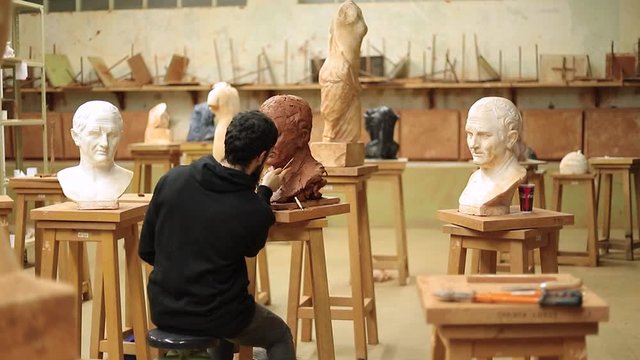 Large Shot of a Sculptor finishing a bust of cicero clay in an art studio