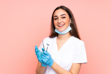 Woman dentist holding tools isolated on pink background applauding