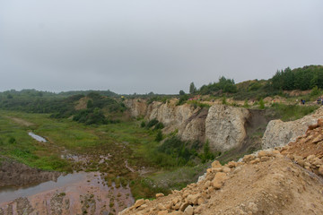 Landscape view of limestone quarry with high cliffs and canyons, and water