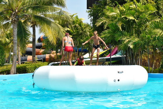 A Water Trampoline In The Water Park. Funny Kids On Inflatable Trampoline.