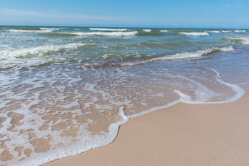 Steep sand shore beach with clouds and blue sky