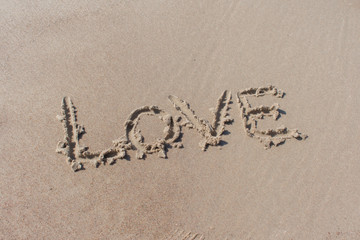 Text ''love'' written in beach sand