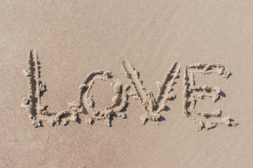 Text ''love'' written in beach sand