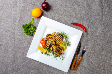 Sturgeon steak with vegetables. Delicious sturgeon steaks are grilled and served on a white square...