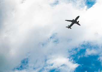 Fototapeta na wymiar Low key of airplane flying in the blue sky for holliday