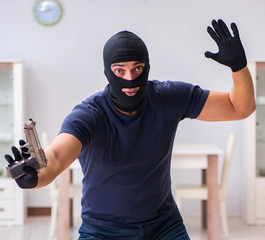 Robber wearing balaclava stealing valuable things