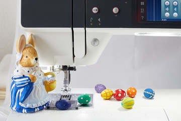 Osterhase mit Korb steht an einer Nähmaschine