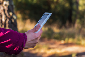 mano de mujer con chaqueta color vino con libro electrónico
