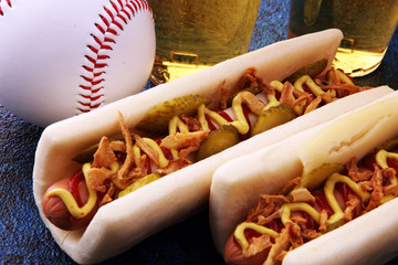 Grilled hot dogs with mustard and ketchup on the table with draft beer. Baseball party food with balls for the playoffs