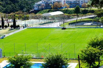 Obraz premium top view of a two small football fields in Benahavis Andalucia Spain, lawnmower cutting grass on the football stadium, beautiful colorful nature and stunning green