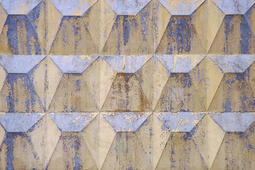 Old faded shabby repeatedly painted concrete fence with relief.