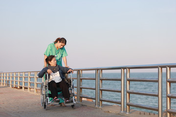 Asian senior woman sitting on the wheelchair  with woman in doctor uniform in the park hospital