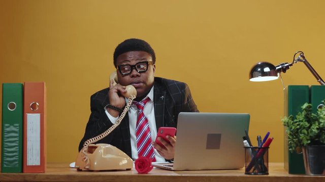 Smart attentive afro-american executive talks on telephone call solving business tasks problem using smartphone device calling at modern office corporation.
