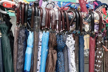 Many different umbrellas displayed for sale on a street on a rainy day