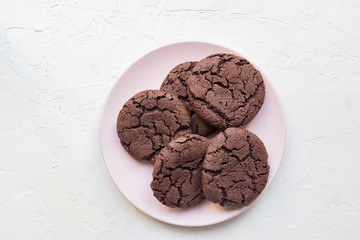 Top view of chocolate chip cookies on a pink plate on white concrete background. From above. copy space