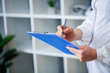 Doctor holds a patient's medical record in his office