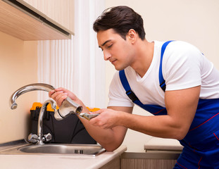Young repairman working at the kitchen