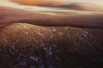 Fotobehang Chocoladebruin Sunset above Winter landscape aerial view, snow covered pine tree forest mountains  © Annatamila