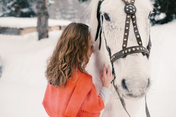 Beautiful woman with white horse in winter fir forest