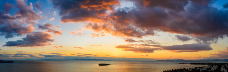 Weites Aerial Panorama eines bewölkten Sonnenunterganges über dem Meer mit von der Sonne rot angestrahlten Wolken