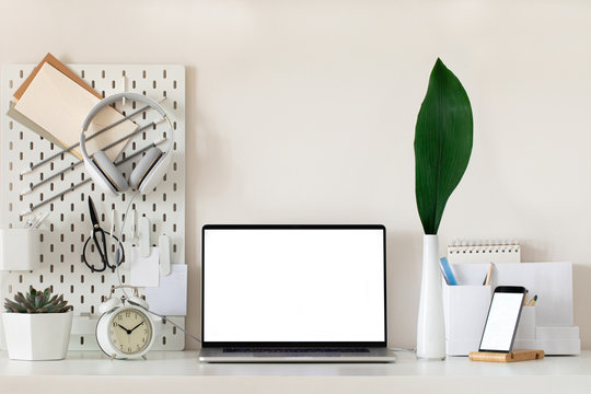 Laptop with blank white screen on office desk interior. Stylish gold workplace mockup table view.