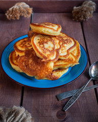 A slide of freshly baked fritters on a blue ceramic plate standing on a wooden tray