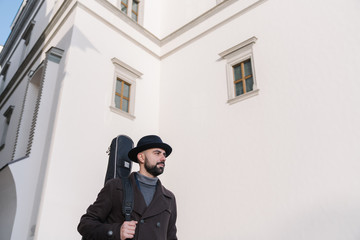 Naklejka premium Portrait of male artist walking with guitar on the street