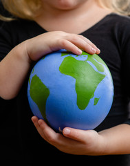 Close up little girl holds planet in her hands. Ecology concept